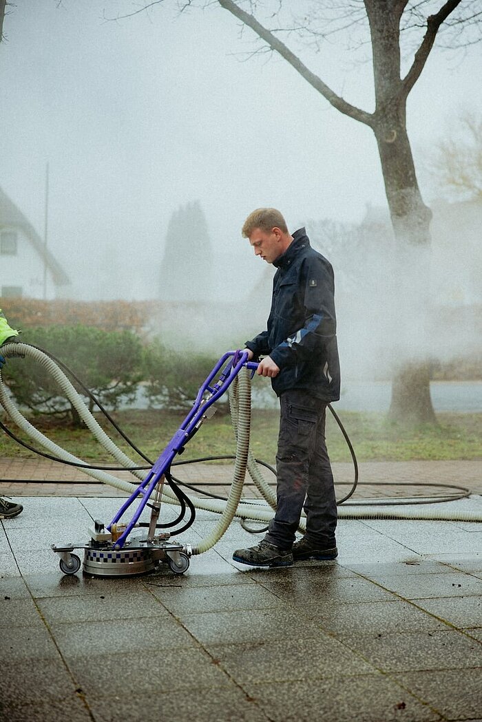 Ein Experte der Malergesellschaft Holzmüller macht eine professionelle Steinflächenreinigung mit Heißwasser-Hochdruckreiniger.